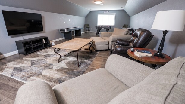 A living room with a flat-screen TV, a pool table, a sofa, and a coffee table. - Beautiful 4-Bedroom Modern Farmhouse located outside of Saint Joseph, IL (Saint Joseph)