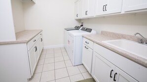 A laundry room with a washing machine, a sink, and cabinets. - Beautiful 4-Bedroom Modern Farmhouse located outside of Saint Joseph, IL (Saint Joseph)