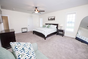 A bedroom with a bed, a nightstand, a dresser, a ceiling fan, a window, and a mirror. - Beautiful 4-Bedroom Modern Farmhouse located outside of Saint Joseph, IL (Saint Joseph)