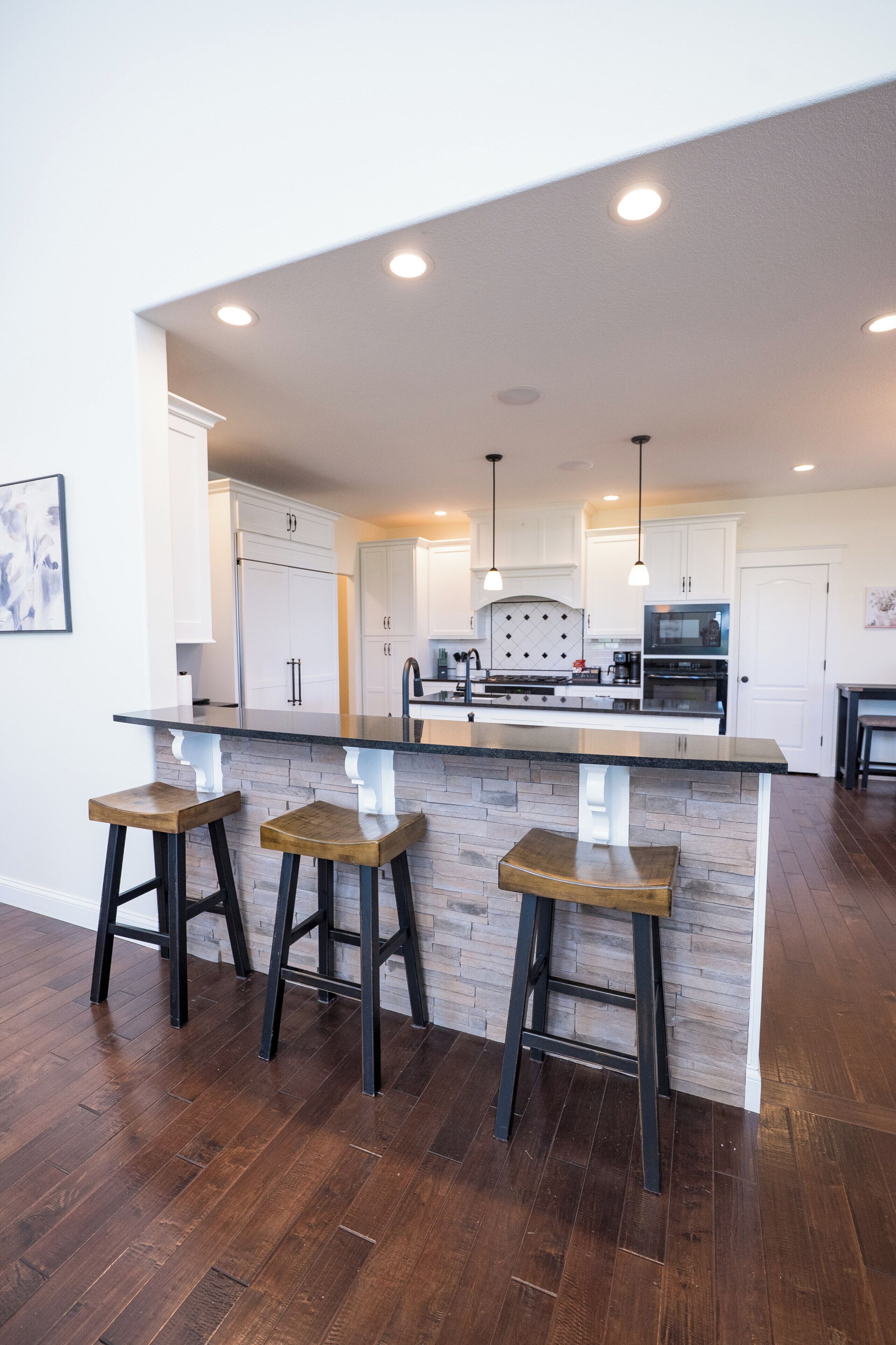 A modern kitchen with a central island, bar stools, and a dining area.