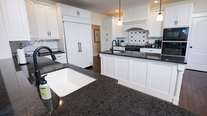 A modern kitchen with white cabinetry, a granite countertop, and stainless steel appliances. - Beautiful 4-Bedroom Modern Farmhouse located outside of Saint Joseph, IL (Saint Joseph)