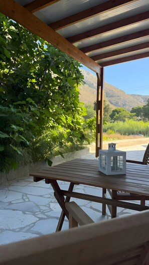Ein überdachter Außenbereich zum Sitzen mit einem Tisch, einer Laterne und Blick auf eine Berglandschaft.