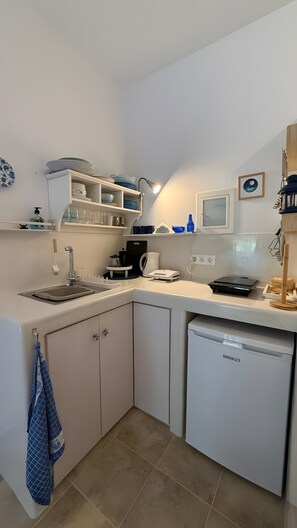 Eine kompakte Küche mit Spüle, Kaffeemaschine, Mikrowelle und Geschirrspüler.
