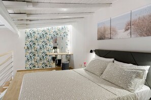 Ein Schlafzimmer mit einem Bett, einem Nachttisch, einer Lampe, einem Fenster mit Blick und einer Wand mit tropischem Wandpapier.