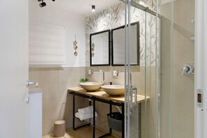 Ein modernes Badezimmer mit Duschkabine aus Glas, einem Doppelwaschbecken und einer Toilette.