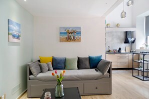 Una sala de estar moderna con un sofá, una mesa de centro con un florero y una zona de cocina con armarios y encimera.