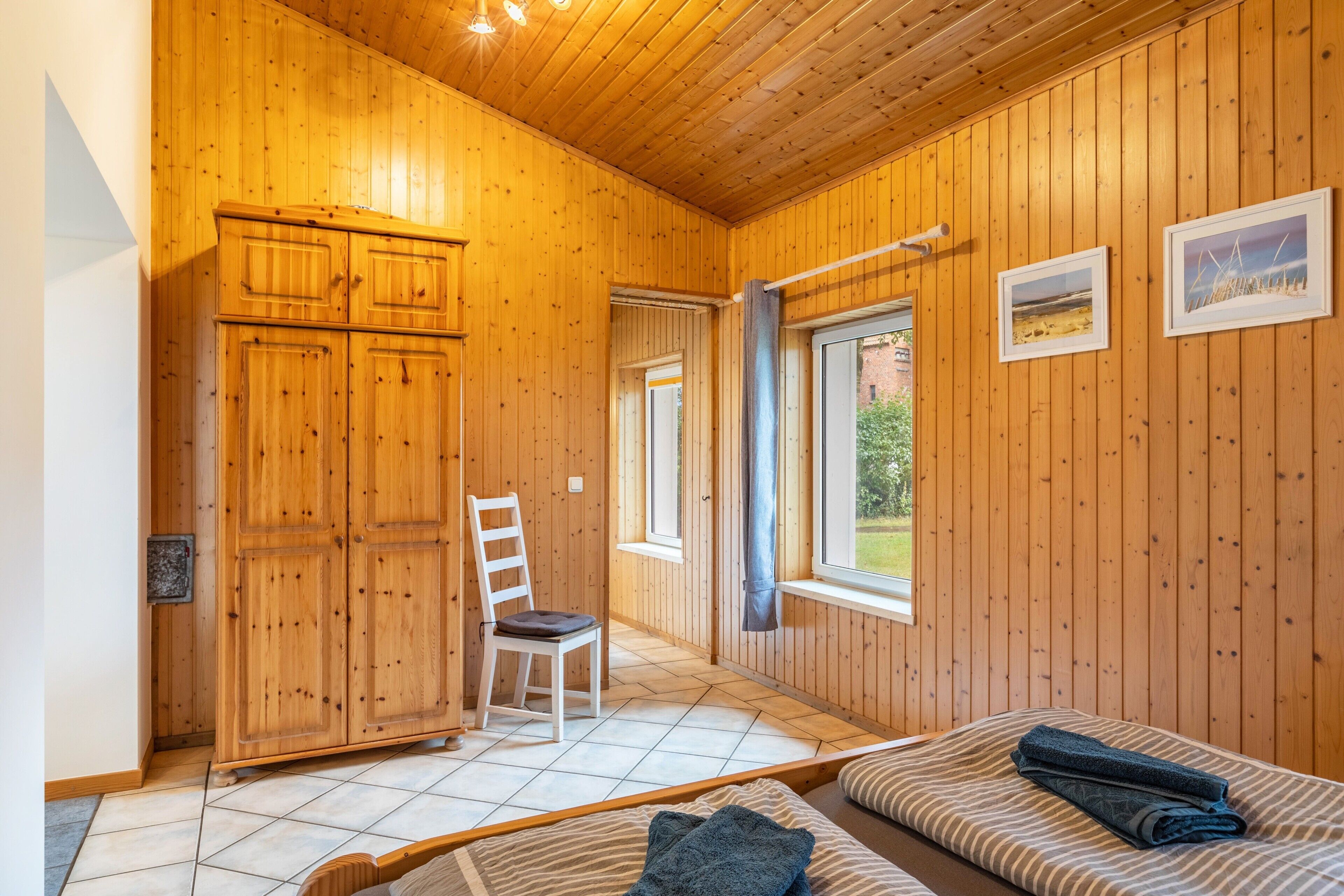 Ein Holzinterieur mit einem Bett, einem Sessel und einem Kleiderschrank.
