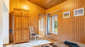 Ein Holzinterieur mit einem Bett, einem Sessel und einem Kleiderschrank.