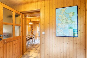A wooden interior with a map on the wall, a dining area, and a door with frosted glass panels.