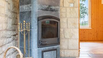 A stone fireplace with a glass door, a candelabra, and a wicker basket.