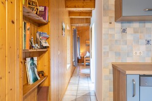 A wooden interior with a kitchen area, a hallway leading to a bedroom, and a bathroom with a shower.