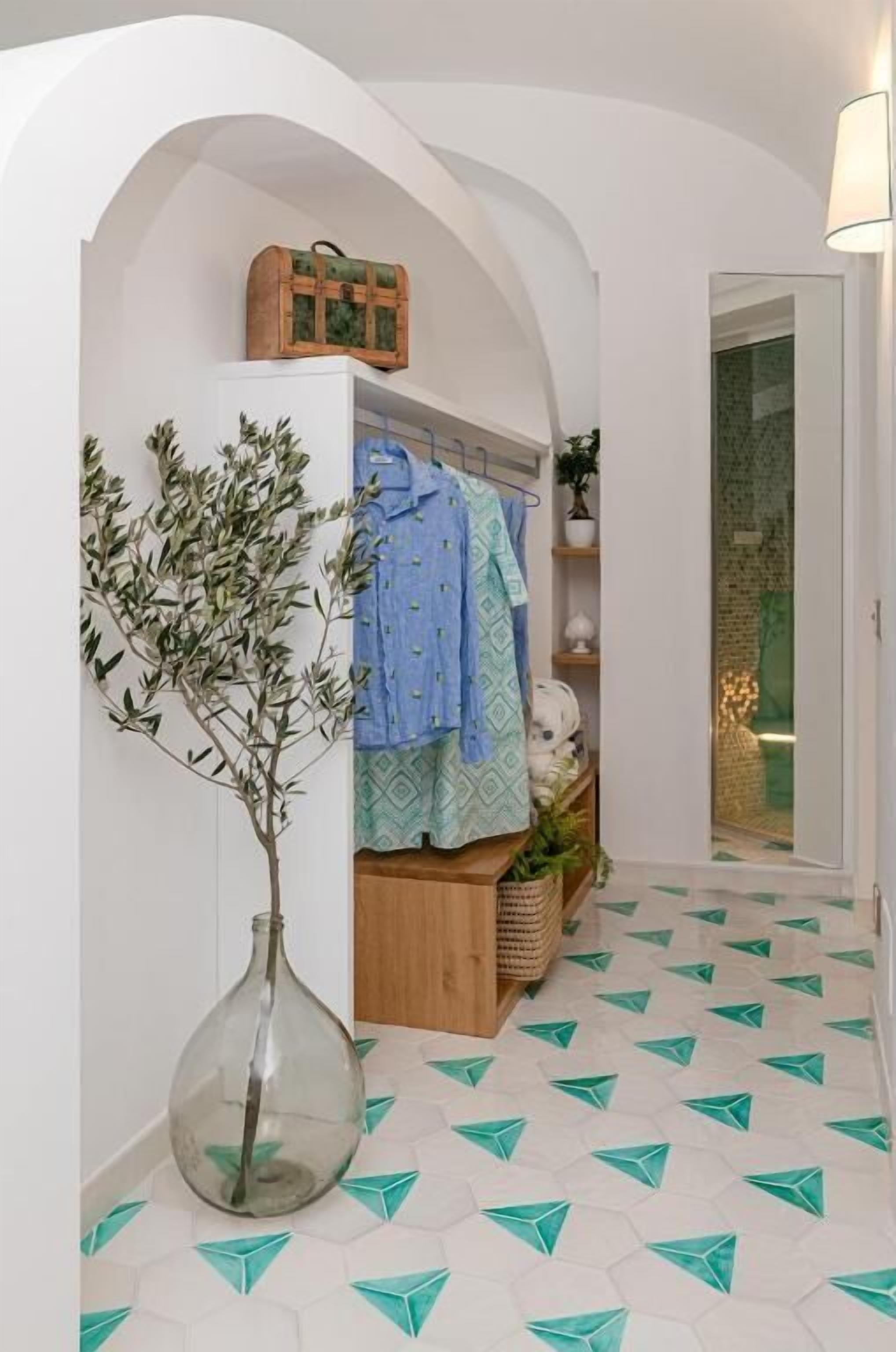 A hallway with a glass vase, a plant, a wooden cabinet, and a door leading to another room.