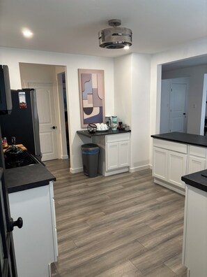 A modern kitchen with white cabinetry, a black countertop, and a stainless steel refrigerator. - 	
Quiet Executive Retreat | Balcony, Parking, Near Hospital & UdeM” (Moncton)