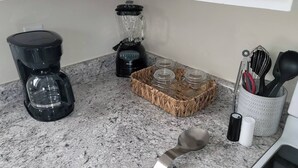Una cuina amb cafetera, batedora i prestatges d'espècies.