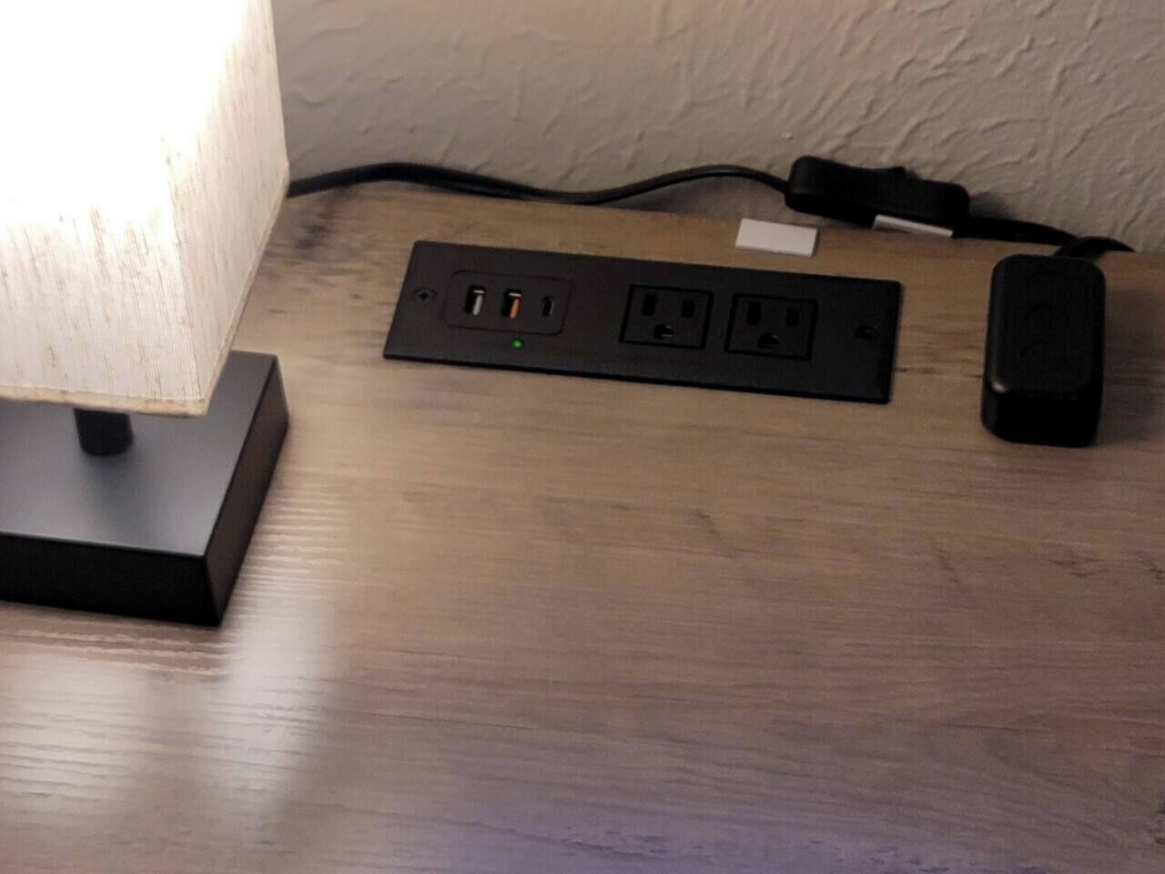 Una regleta amb diverses preses i ports USB sobre una superfície de fusta.