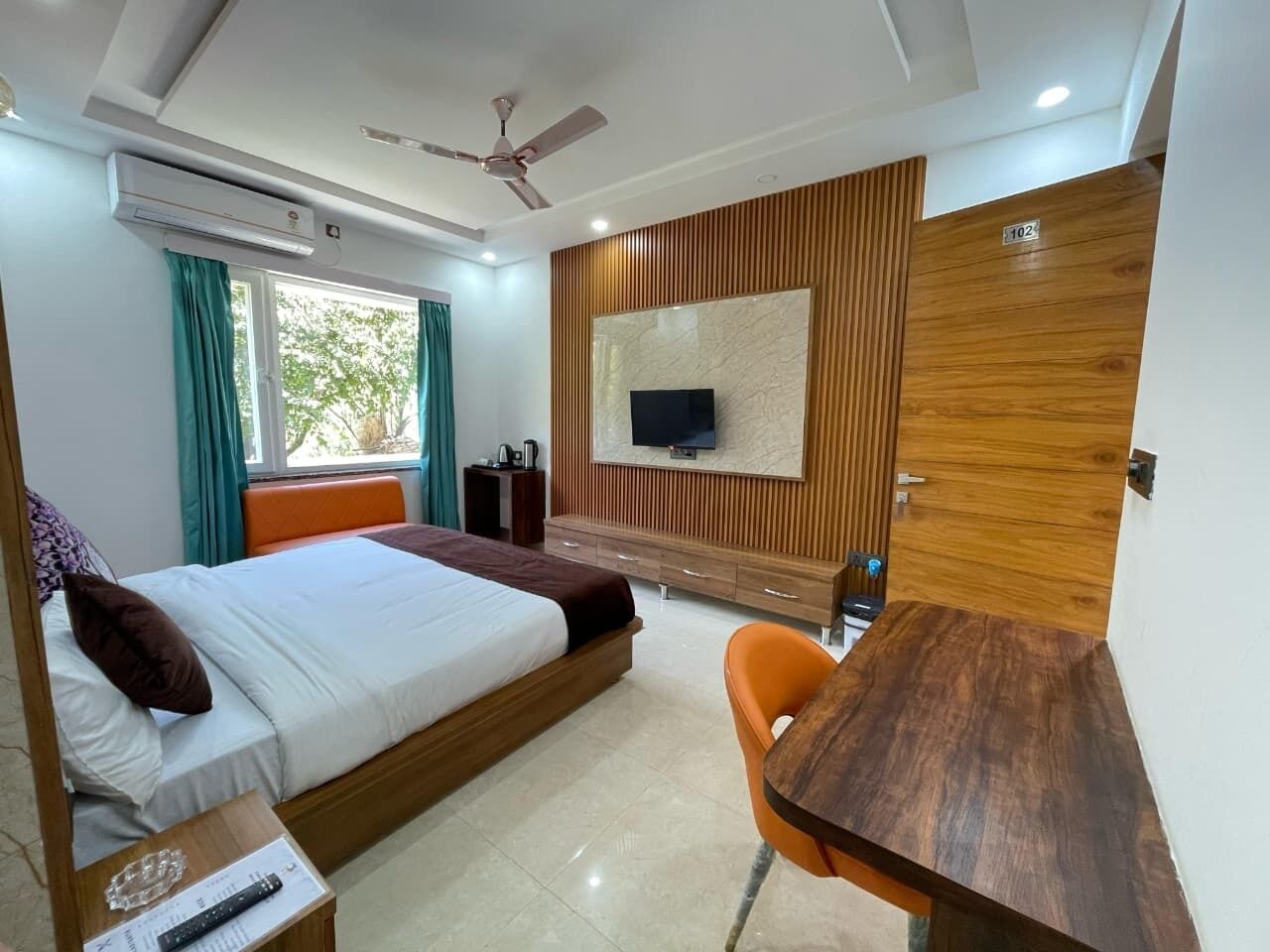 Una habitación de hotel con cama, escritorio, silla, televisor y armario.