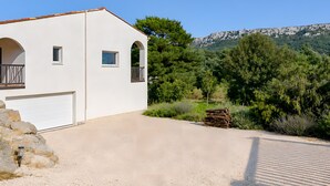 Een wit gebouw met een garage, balkon en uitzicht op een bergachtig landschap.