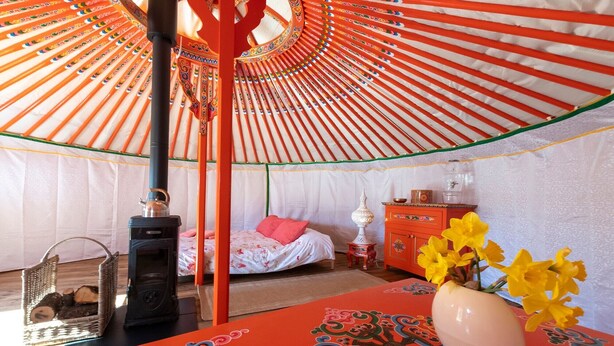 Quarto com cama, mesa com um vaso, aquecedor e dispensador de água.