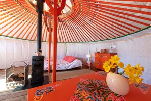 Una habitación con una cama, una mesa con un florero, un calentador y un dispensador de agua.