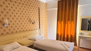 Ein Hotelzimmer mit zwei Betten, einem Schreibtisch, einem Spiegel und einer Wand mit Muster.