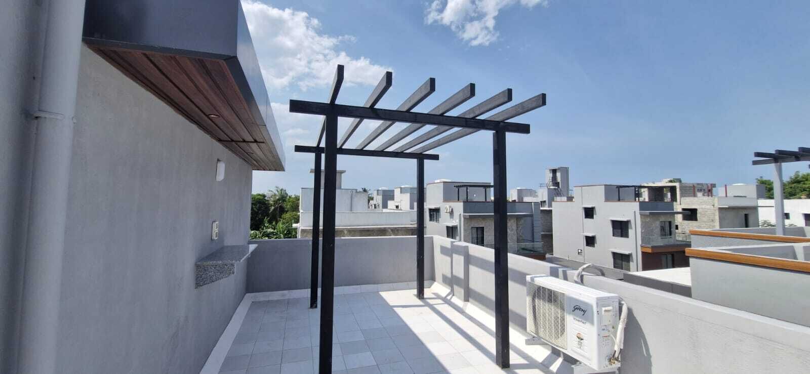 Eine Dachterrasse mit einer Pergola, Klimaanlagen und Blick auf die umliegenden Gebäude.