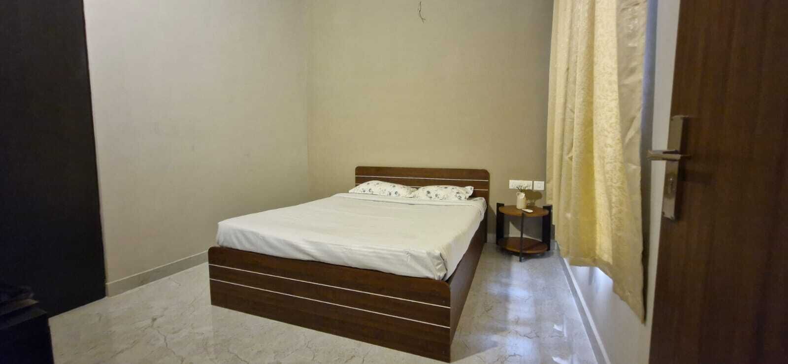 A small, neatly arranged bedroom with a single bed, a bedside table, and a door.
