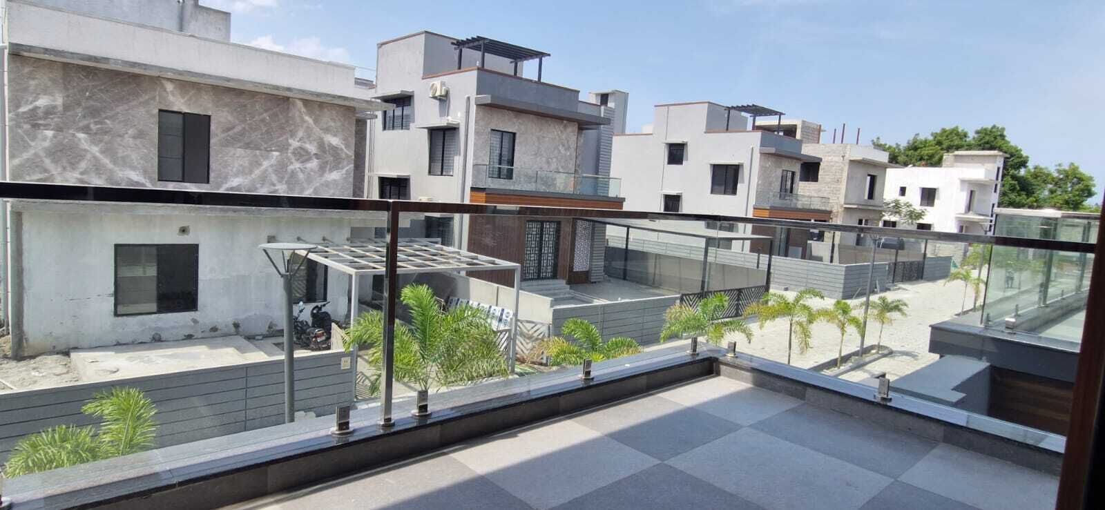 A modern building with a glass balcony, a clear view of the surrounding area, and a paved terrace.