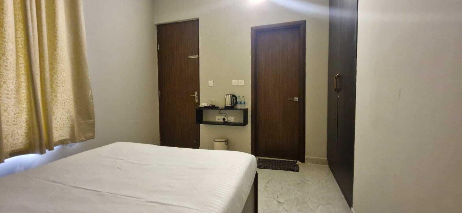 Une chambre d’hôtel avec un lit, une petite table de chevet, un miroir et deux portes.