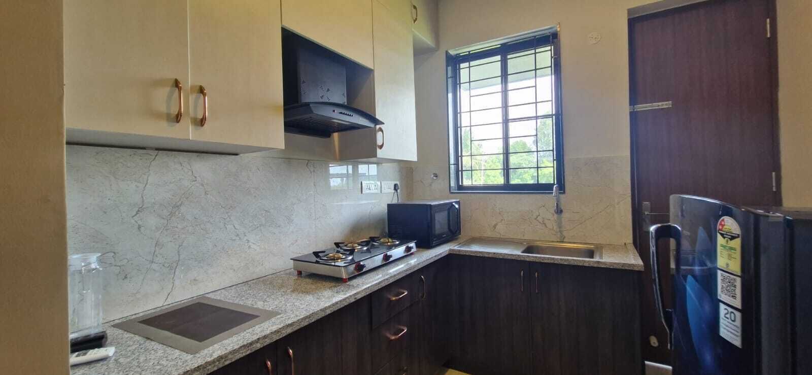 Una cucina compatta con piano cottura a gas, forno a microonde e frigorifero.