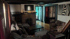 A living room with a sofa, armchairs, a coffee table, a fireplace, a television, and a patterned wall.