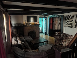 Una sala de estar con sofá, sillones, una mesa de centro, chimenea, televisor y un papel tapiz estampado.