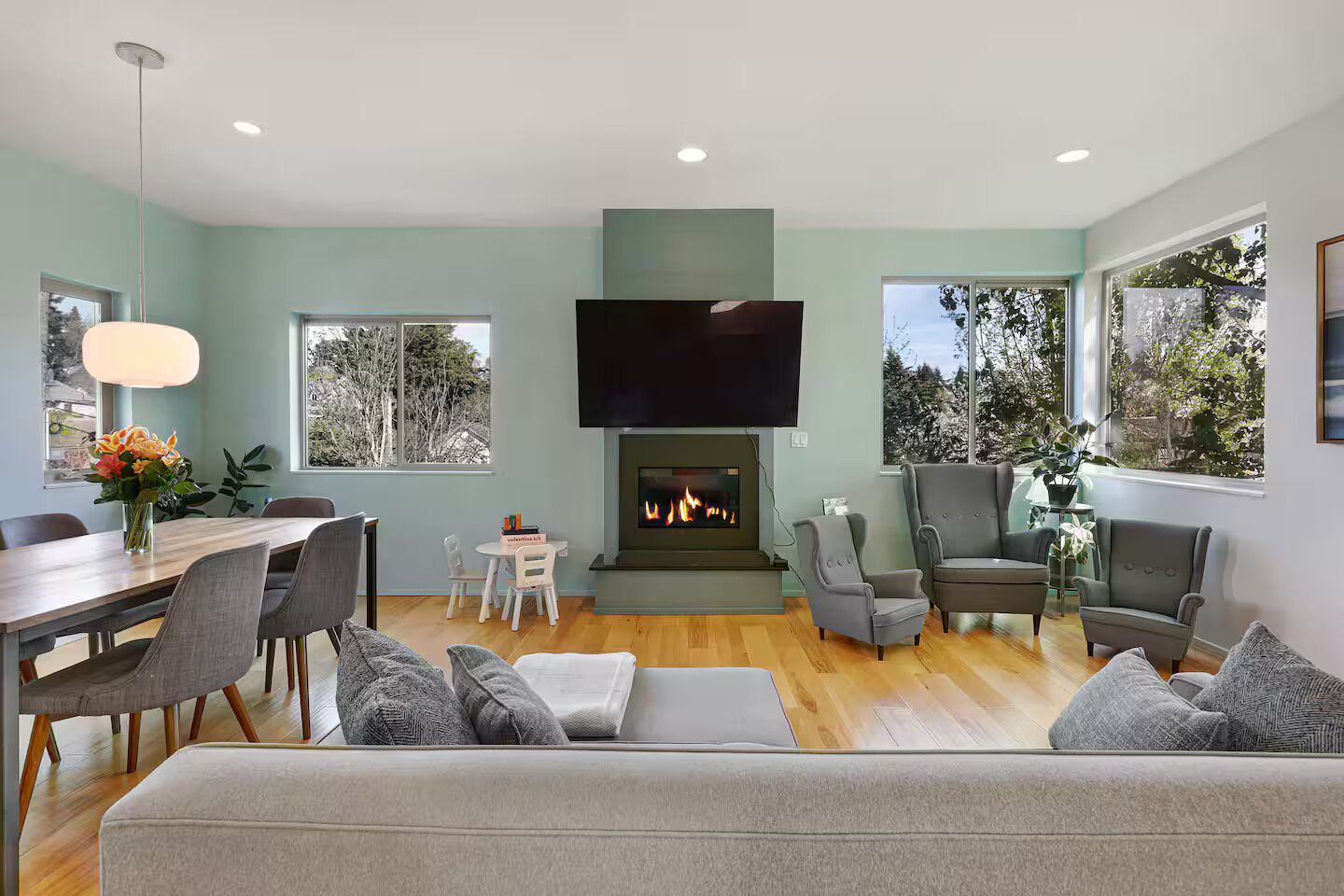 A modern living room with a fireplace, seating area, and a dining table.