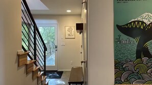 A hallway with a staircase, a door, and a poster of the FIFA World Cup 26. - Walk to Light Rail, Stylish Retreat w/Parking + AC (Seattle)