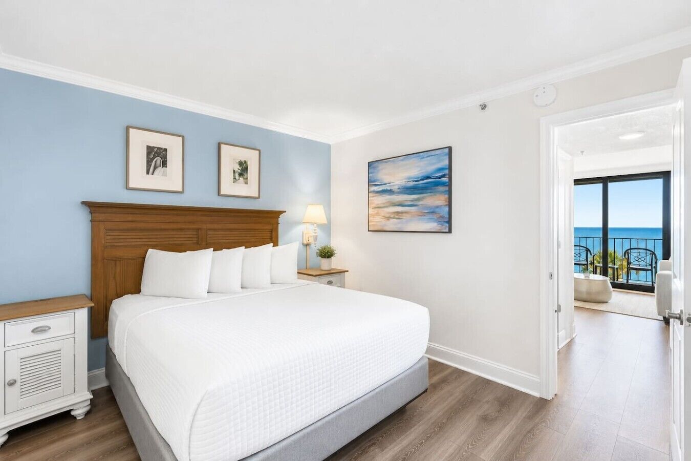 A hotel room with a bed, a nightstand, a lamp, and a painting on the wall.