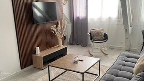 Uma sala de estar moderna com televisão de tela plana, painel de parede em madeira, sofá e mesa de centro.