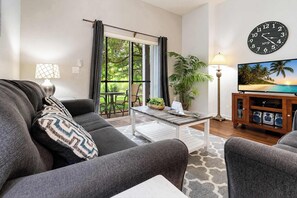 Ein Wohnzimmer mit Sofa, Couchtisch, Fernsehtisch und einer großen Wanduhr.