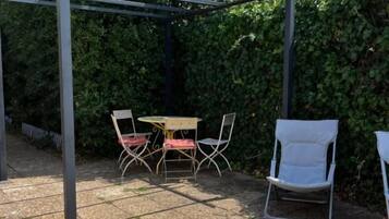 Un espacio de patio al aire libre con una pérgola, una mesa y cuatro sillas.