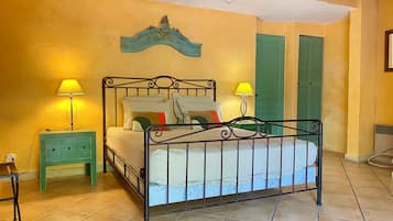 A bedroom with a bed, two nightstands, a wall-mounted lamp, and a green door.