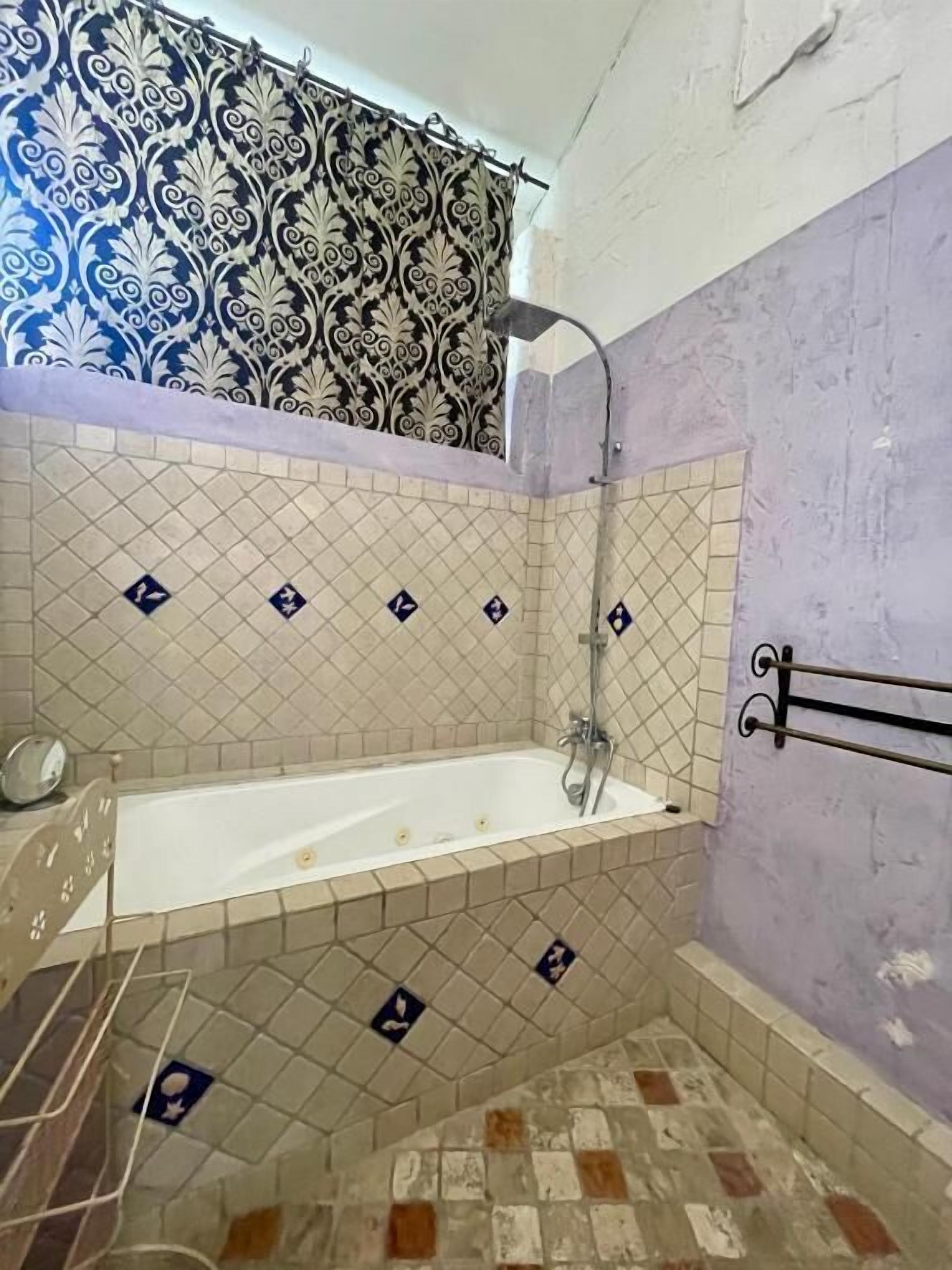 A bathroom with a bathtub, shower, and tiled walls.