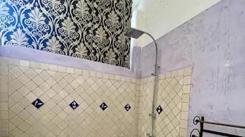 A bathroom with a bathtub, shower, and tiled walls.
