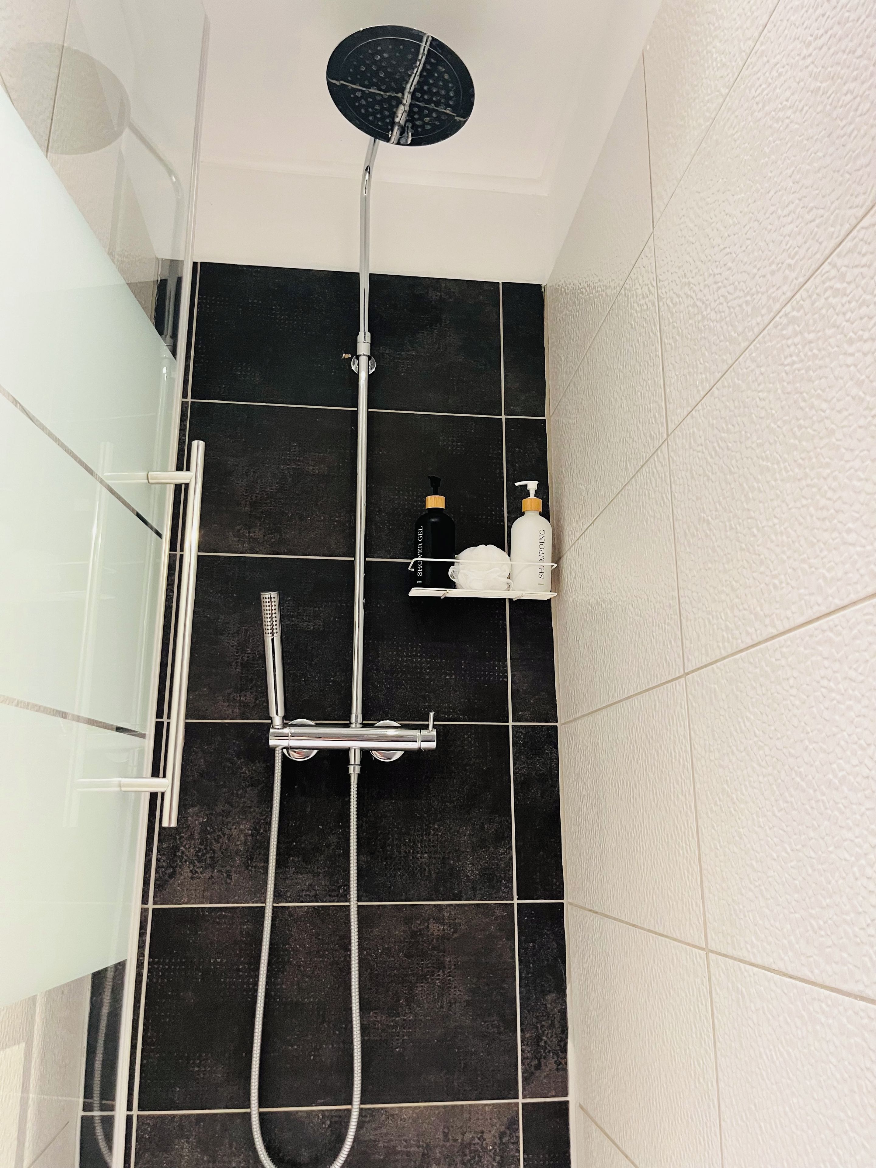 A shower with a handheld showerhead and a wall-mounted faucet.
