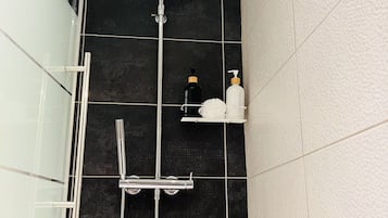 A shower with a handheld showerhead and a wall-mounted faucet.