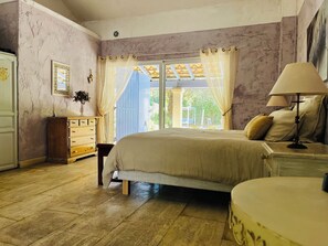 Un dormitorio con cama, mesita de noche, cómoda y ventana con cortinas.