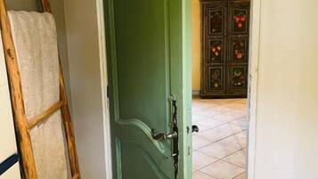 A doorway leading to a room with a tiled floor, a wooden ladder, and a white towel hanging on the wall.