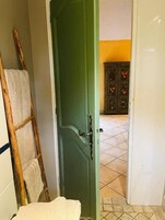 Un vano de puerta que da a un cuarto con piso de baldosas, una escalera de madera y una toalla blanca colgada en la pared.