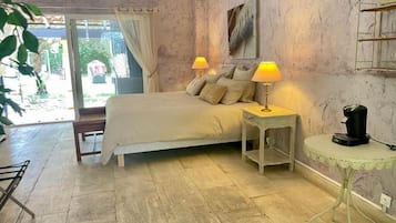 Un dormitorio con cama, lámparas de noche, cafetera y vista a través de un ventanal.