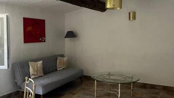 Una habitación con un sofá gris, una mesa de vidrio y una silla.