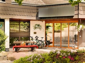 A building entrance with a bench, bicycles, and a hanging flower basket. - 2 Person Holiday Park Home in Willingen (Willingen)