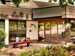 A building with a covered patio area, a bench, and a hanging flower basket. - 2 Person Holiday Park Home in Willingen (Willingen)