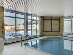An indoor swimming pool with stone walls and large windows. - 2 Person Holiday Park Home in Willingen (Willingen)